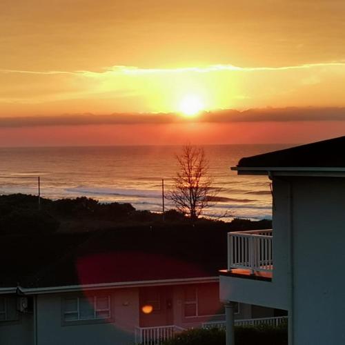a sunset over the ocean from a house at Hello Holiday at 4 Boboyi Mangrove Beach Estate in Port Shepstone