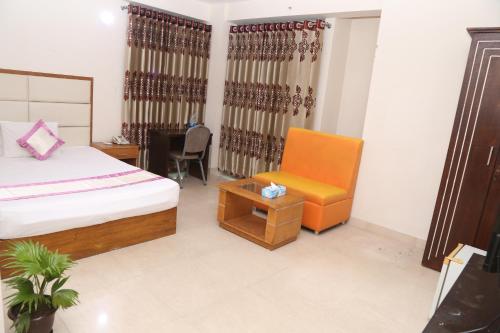 a bedroom with a bed and a chair and a table at Platinum Hotel Ltd in Dhaka
