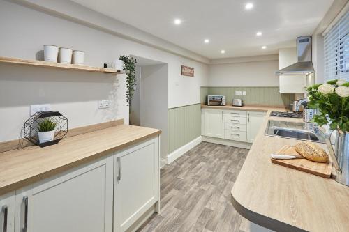 a kitchen with white cabinets and a wooden counter top at Host & Stay - Sion Hall Cottage in Alnwick
