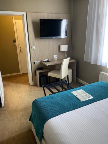 Cette chambre comprend un lit, un bureau et une télévision. dans l'établissement Hotel Normandy, à Vernon
