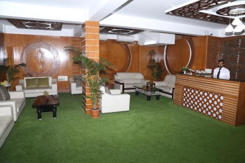 a living room with white furniture and green carpet at Platinum Hotel Ltd in Dhaka