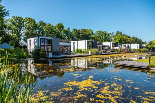 a row of modular homes next to a pond at EuroParcs Bad Hoophuizen in Hulshorst