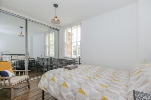 a bedroom with a bed and a chair and windows at Flat 2, 158 Abingdon Road in Oxford