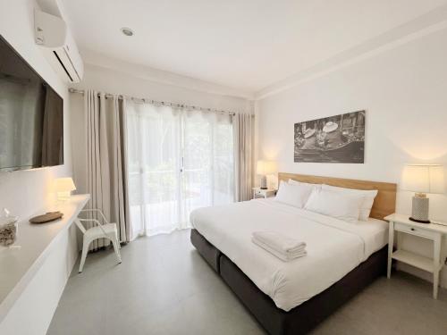 a white bedroom with a large bed and a window at Isara Khao Lak in Khao Lak