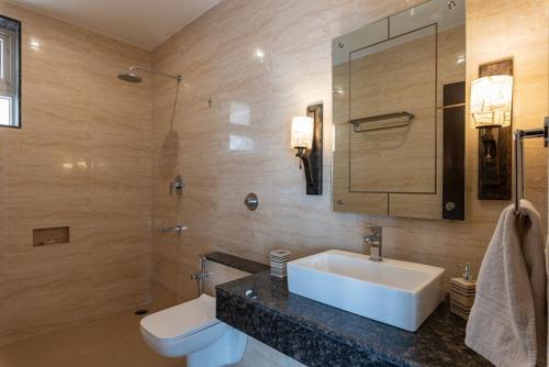 a bathroom with a sink and a toilet and a mirror at Luxurious Villa with Private Swimming Pool, Kids Pool, Games, Private Parking in Calangute