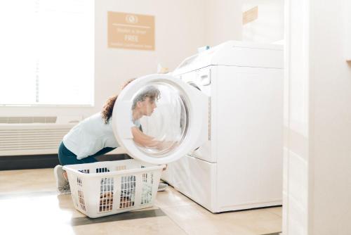 a woman loading a washing machine in a kitchen at Candlewood Suites Apex Raleigh Area by IHG in Apex