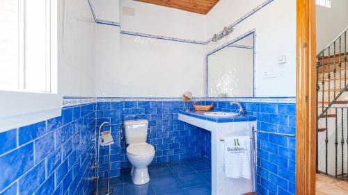 Baño de azulejos azules con aseo y lavamanos en Casa Calera Arbuniel by Ruralidays en Jaén