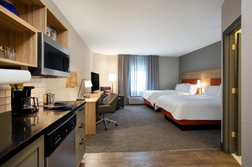 a hotel room with two beds and a desk at Candlewood Suites Apex Raleigh Area by IHG in Apex
