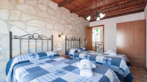 3 camas en una habitación con una pared de piedra en Casa Calera Arbuniel by Ruralidays en Jaén