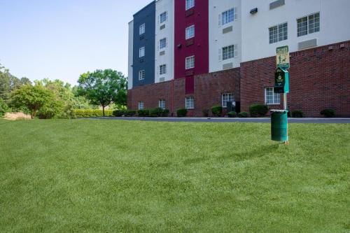 a green trash can in the grass in front of a building at Candlewood Suites Apex Raleigh Area by IHG in Apex