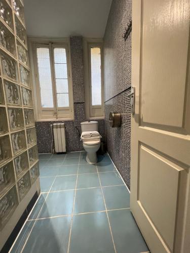 baño con aseo y suelo de baldosa azul en Hostal Abaaly, en Madrid