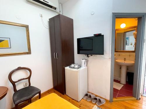 a room with a tv and a chair and a bathroom at The Only One Suites in Niš