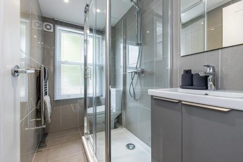 ein Bad mit einer Dusche und einem Waschbecken in der Unterkunft Flat 3, 158 Abingdon Road in Oxford