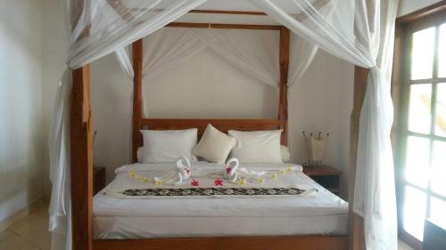 a bedroom with a white bed with a canopy at Villa Nirwana in Lovina