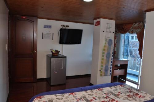 a bedroom with a bed and a tv on a wall at Hotel Suite Imperial in Tunja