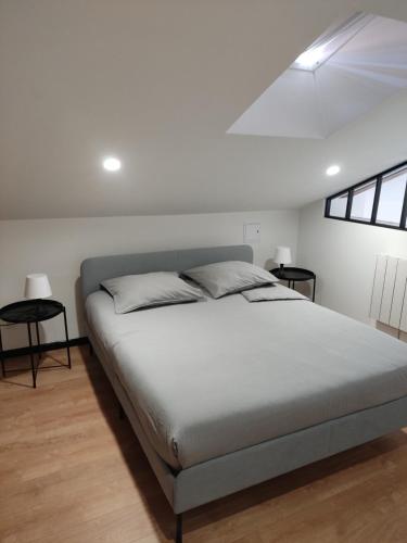 a bedroom with a large bed and two tables at Résidence du Lavoir in Saint-Étienne-de-Saint-Geoirs