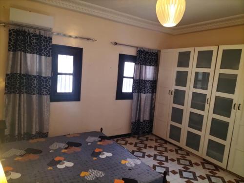 a bedroom with a bed and two windows at Maison d'Hôtes entière Cité Douane Golf Dakar in Dakar