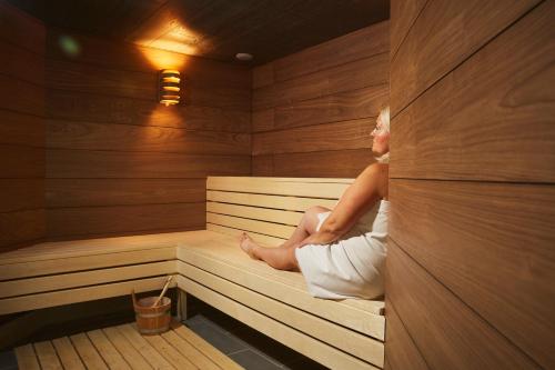 a woman is sitting in a sauna at Thermal Resort Hotel Lendava in Lendava