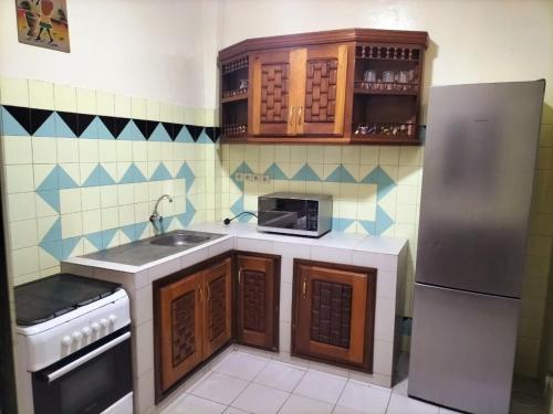 a small kitchen with wooden cabinets and a refrigerator at Maison d'Hôtes entière Cité Douane Golf Dakar in Dakar