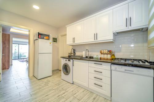 a kitchen with white cabinets and a washer and dryer at Nakas Suites in Fethiye