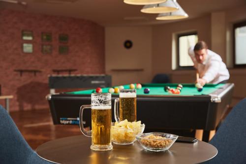 a table with two glasses of beer and a pool table at Thermal Resort Hotel Lendava in Lendava