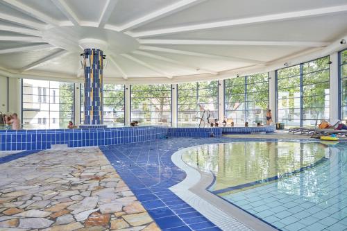 einen großen Pool mit blauen Fliesenböden und Fenstern in der Unterkunft Thermal Resort Hotel Lendava in Lendava
