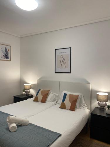 1 dormitorio con 1 cama blanca grande y 2 lámparas en Apartamento Amplio y Central a pie de Playa la Concha, en San Sebastián