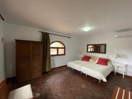 a bedroom with a bed with two red pillows at Casas Rurales Monasterio de Rocamador in Almendral