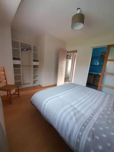 une chambre avec un grand lit et une chaise dans l'établissement Maison de la foret, à Le Theil-en-Auge