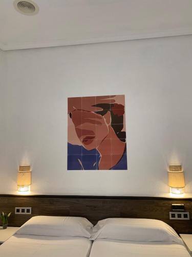 a bedroom with two beds and a painting on the wall at Pensión Donostiarra in Donostia-San Sebastián