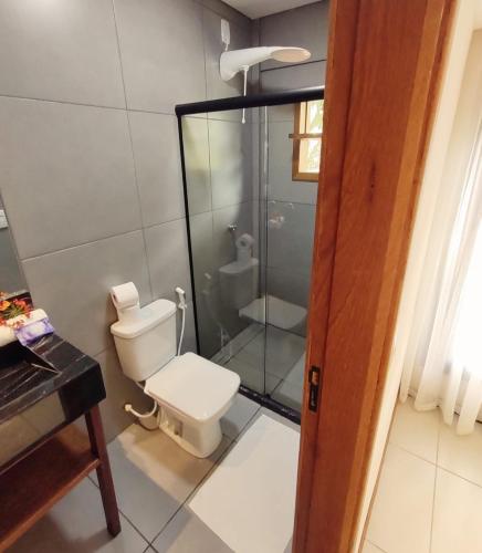 a bathroom with a toilet and a glass shower at i9 Quixaba Flat in Itacaré