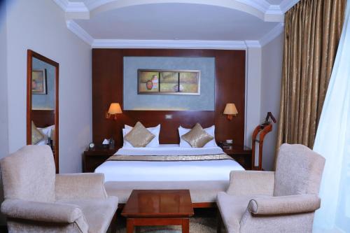 a hotel room with a bed and two chairs at Sidra International Hotel in Addis Ababa