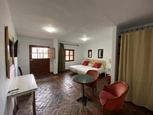 a hotel room with a bed and a table and chairs at Casas Rurales Monasterio de Rocamador in Almendral