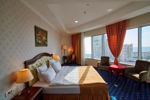 una camera d'albergo con un letto e una grande finestra di Grand Hotel Victory ad Aqtau