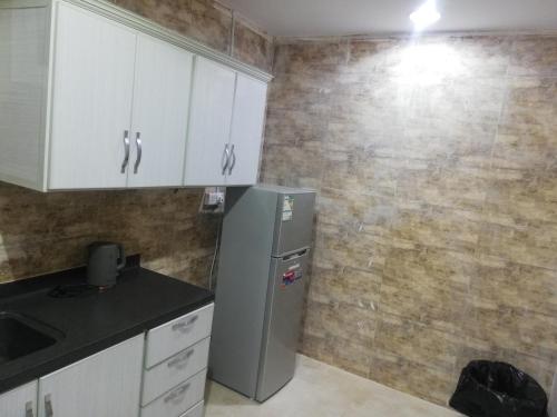 a kitchen with white cabinets and a refrigerator at المغتره للشقق المخدومه in Ad Dawādimī