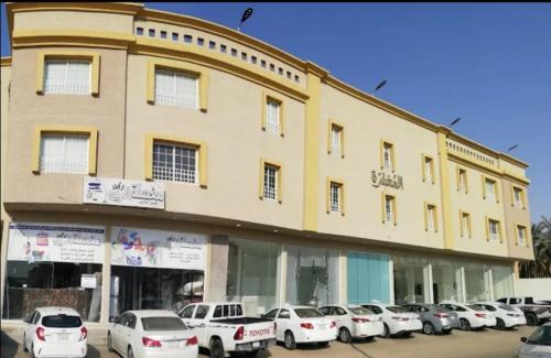 un gran edificio con coches estacionados frente a él en المغتره للشقق الفندقيه en Ad Dawādimī
