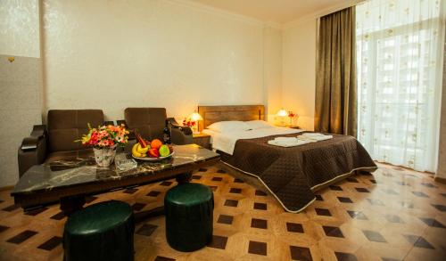 Royal Apartments Batumi في باتومي: غرفة فندقية بسرير وطاولة وكراسي