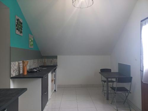 une cuisine avec comptoirs noirs, table et chaises dans l'établissement Les Mansardes l'Appart, à Sarlat-la-Canéda