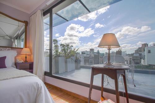 a bedroom with a bed and a large window at Alma Histórica Boutique Hotel in Montevideo