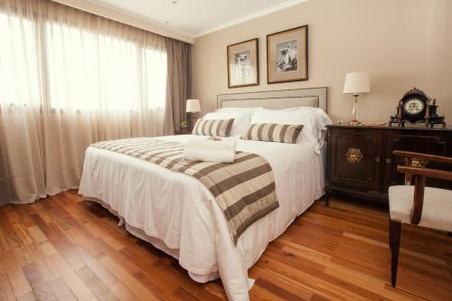 a bedroom with a large white bed with a wooden floor at Alma Histórica Boutique Hotel in Montevideo