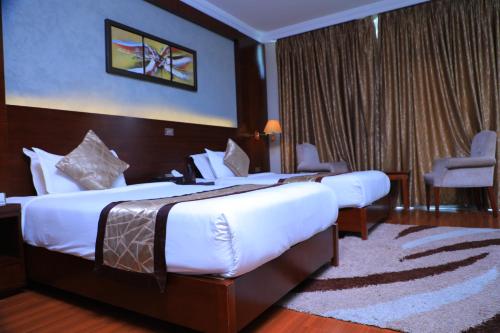 a hotel room with two beds and a chair at Sidra International Hotel in Addis Ababa
