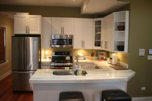 a kitchen with white cabinets and a stainless steel refrigerator at Roscoe Village Guesthouse in Chicago
