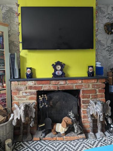 a fireplace with a flat screen tv above it at Quaint & Quirky House Colchester Town Centre in Colchester