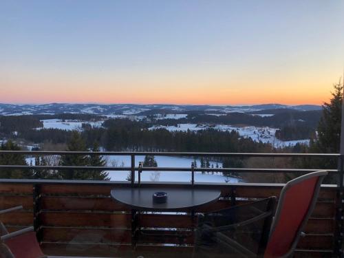 een tafel en stoelen op een balkon met uitzicht op de zonsondergang bij Panorama Bayerwald in Neureichenau