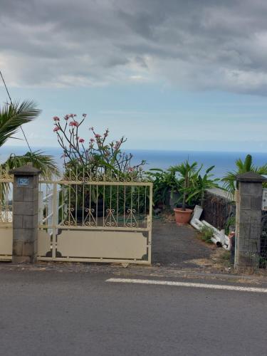 a gate with a fence with the ocean in the background at Nidamour, un logement fait pour vous in Saint-Paul