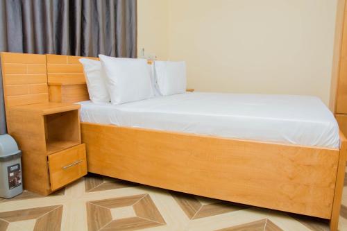 uma grande cama de madeira num pequeno quarto em GIDI LODGE em Tamale