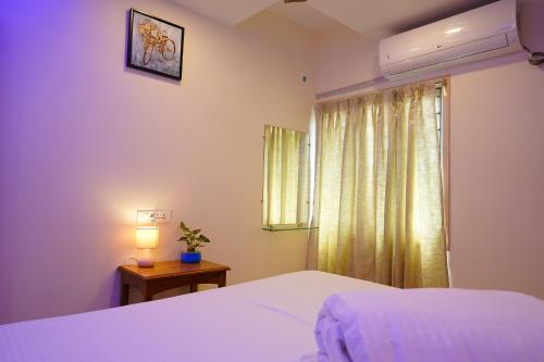 - une chambre avec un lit blanc et une fenêtre dans l'établissement Priya Woodz Homestay, Tirupati, à Tirupati
