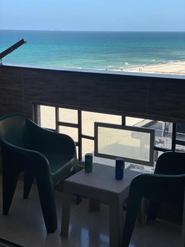 a living room with a table and chairs and the beach at Alzohour Family condo with panoramic sea view in Alexandria