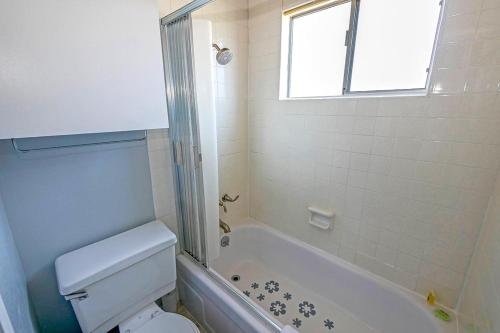 baño con aseo, bañera y ventana en Ala Wai BoulevardApartment 23, en Lake Valley