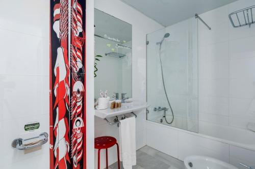 a white bathroom with a red and white tie on the wall at Hotel Del Pintor in Málaga